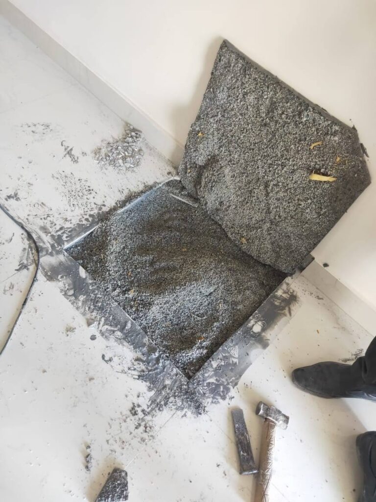Floor tiles lifted during an inspection, showing patchy mortar and hollow gaps beneath